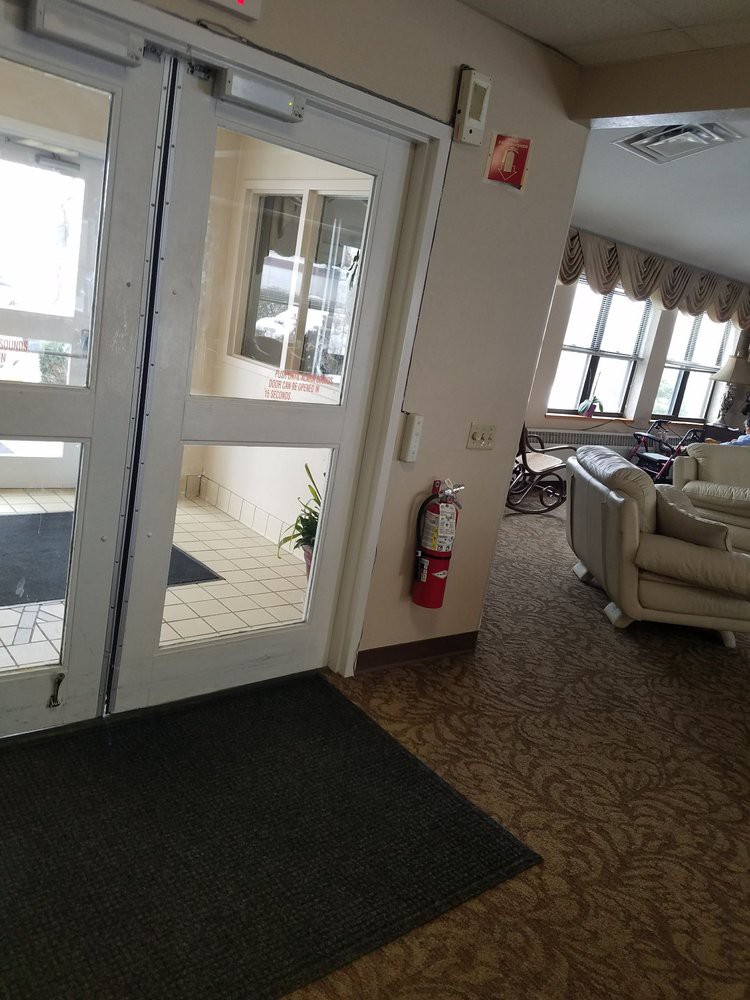 A cozy lobby area with large windows and comfortable seating near a set of glass doors.