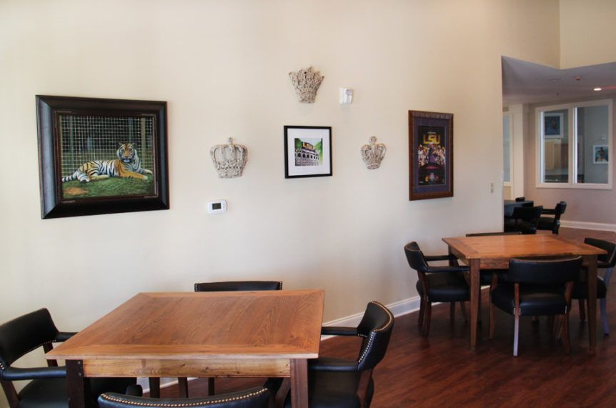 A cozy cafe interior featuring wooden tables, black chairs, and framed artwork on the walls.