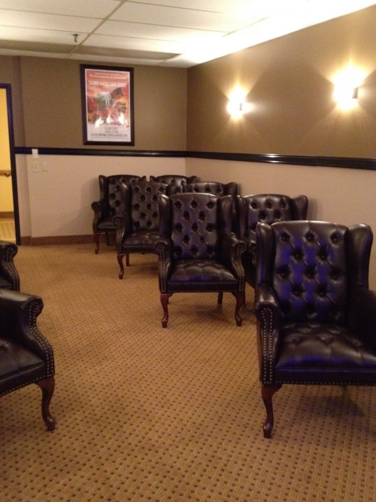 A cozy waiting room with leather chairs arranged in rows, featuring warm lighting and wall art.