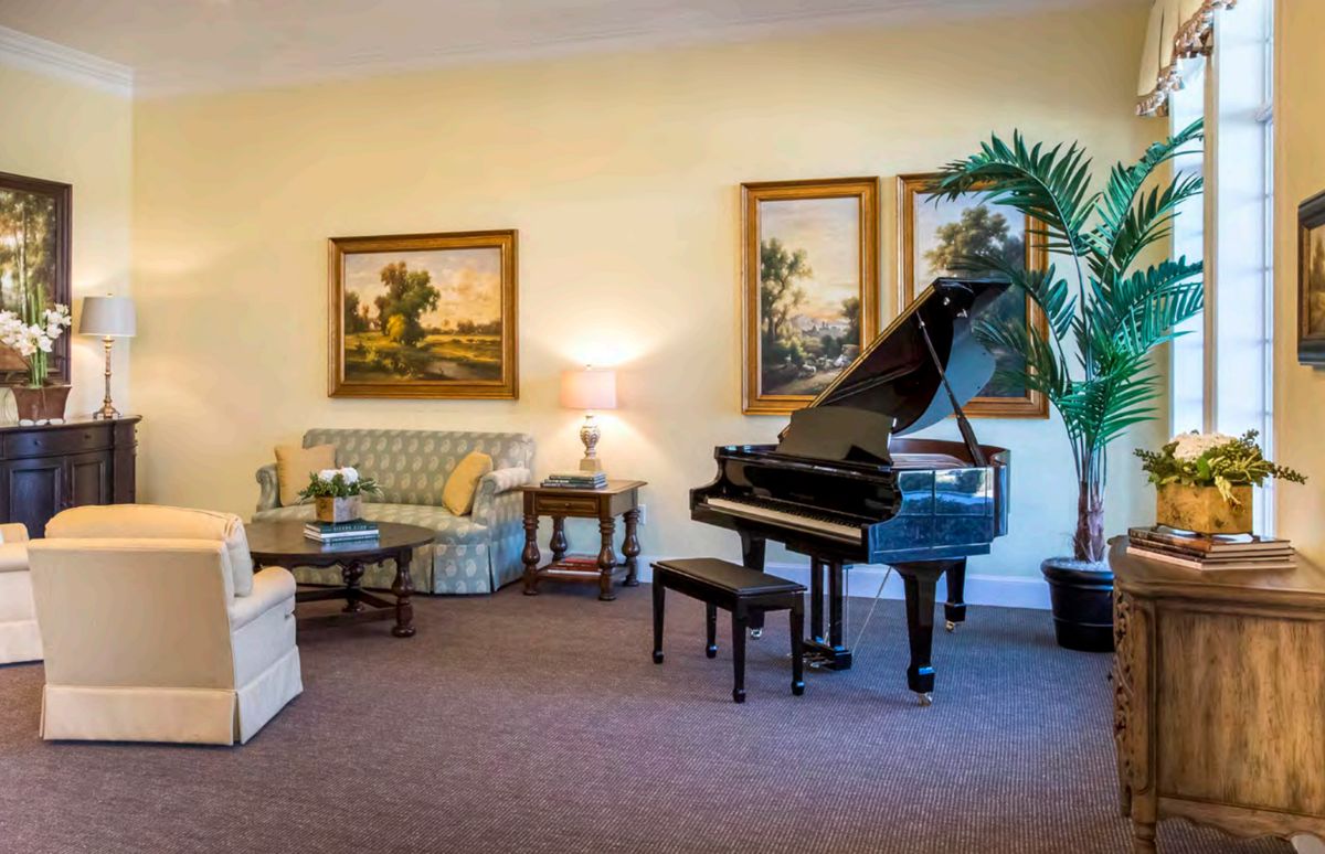A cozy living room featuring a grand piano and elegant artwork on the walls.
