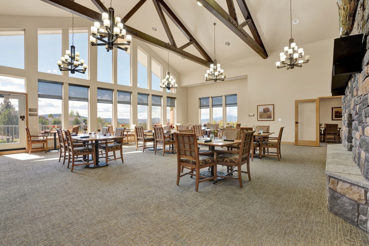 A spacious dining area with large windows, wooden beams, and elegant chandeliers.