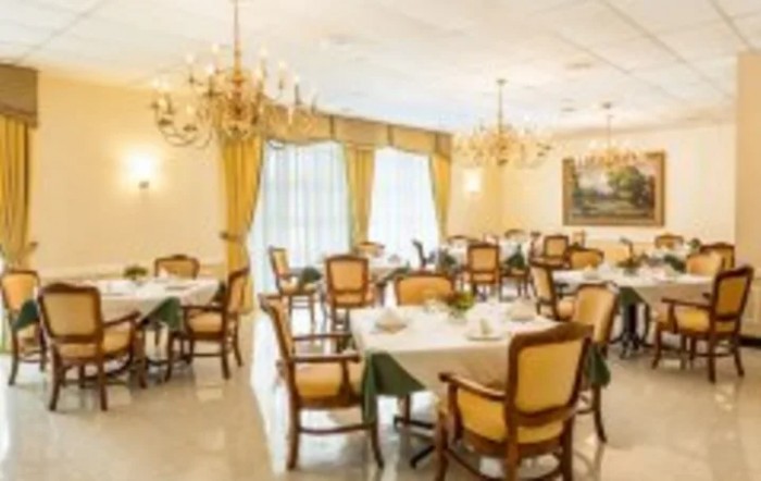 An elegant dining room with chandeliers and neatly arranged tables and chairs.