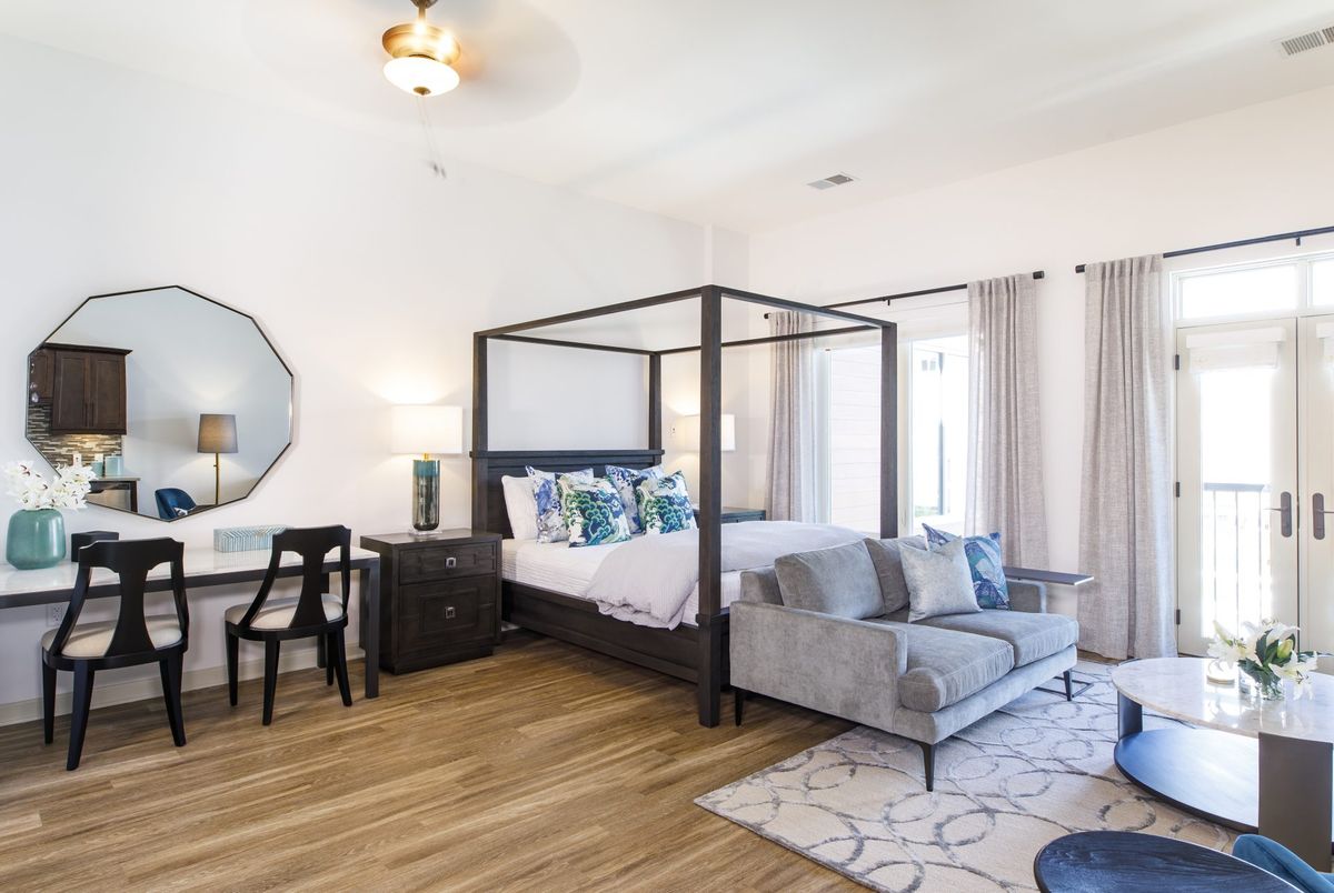 A spacious and modern bedroom with a four-poster bed, stylish furniture, and wooden flooring.