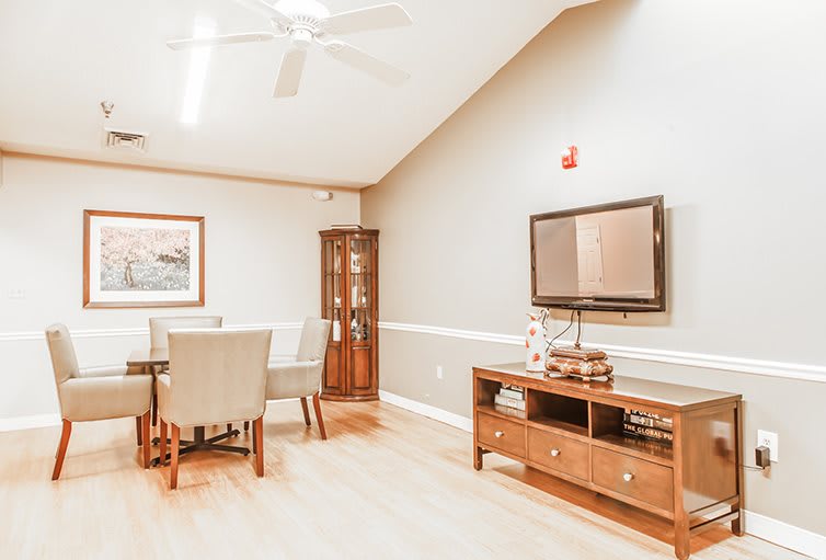 A cozy living room with a dining area, featuring a television, a wooden cabinet, and stylish furnishings.