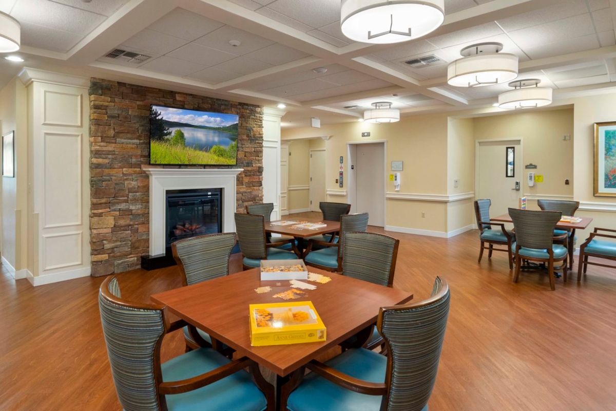 A cozy, well-lit dining area with modern furniture, featuring a stone fireplace and mounted television.