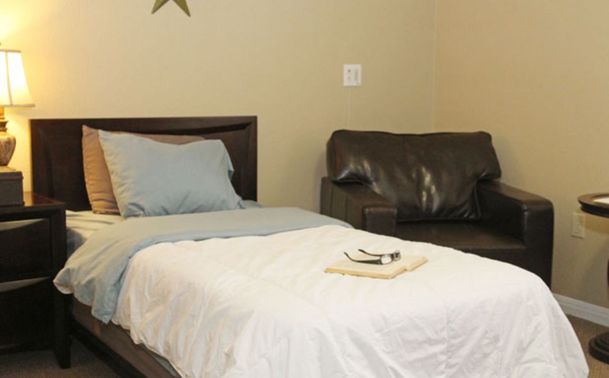 A minimalist bedroom with a bed, pillow, and a couch in the background.