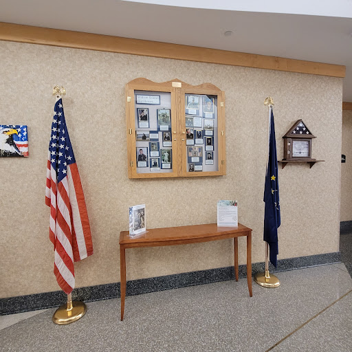 An interior view showcasing the U.S. flag and a state flag, accompanied by a photo display mounted on the wall.