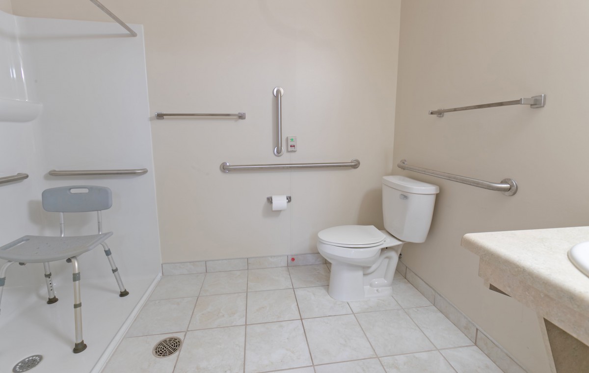 An accessible bathroom with grab bars and a tiled floor.