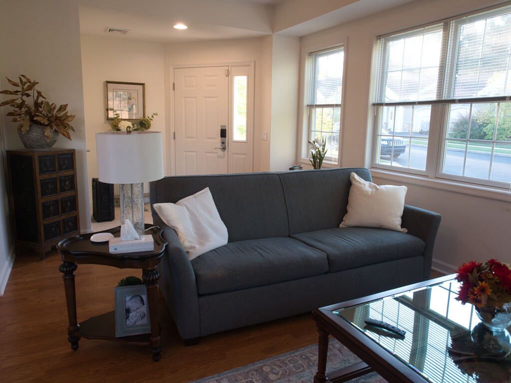 A cozy living room with a comfortable sofa, side table, and natural light streaming through the windows.