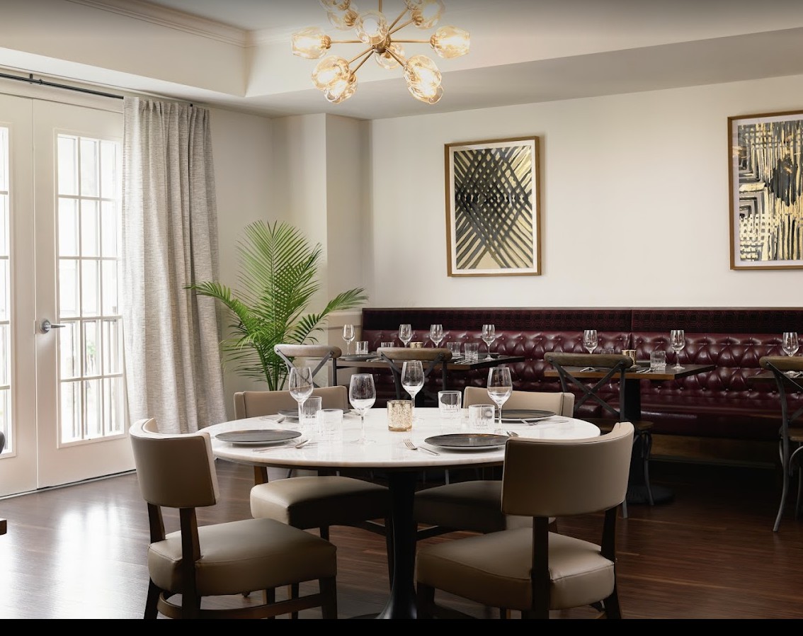 A modern, elegant dining area with stylish table settings and a decorative chandelier.