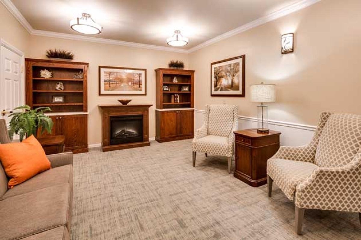 A cozy living room featuring a fireplace, bookshelves, and comfortable seating.