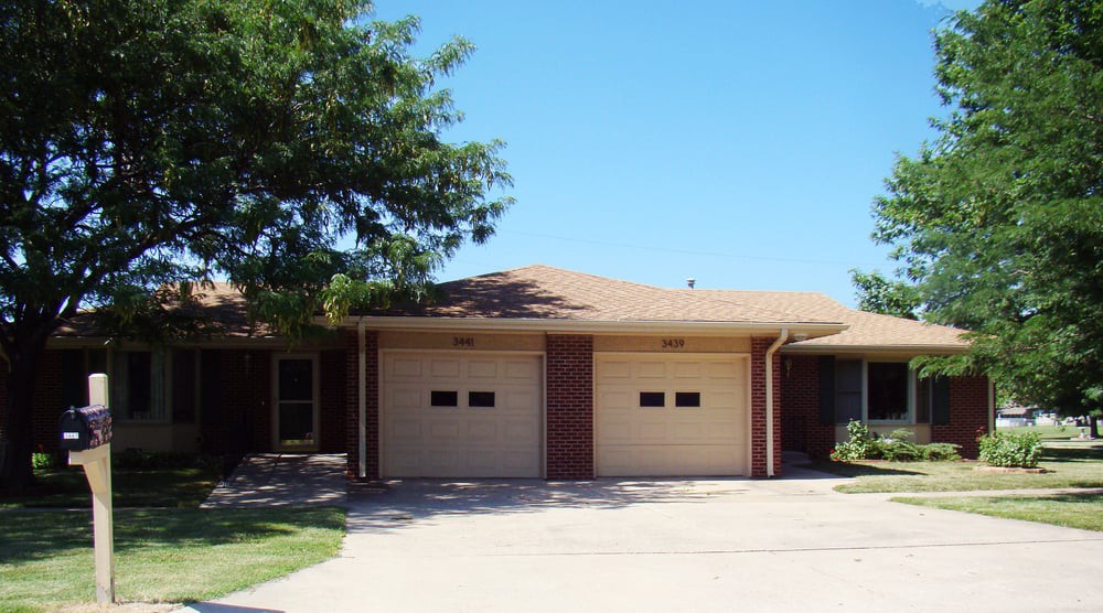 A residential house with a two-car garage under a clear blue sky.