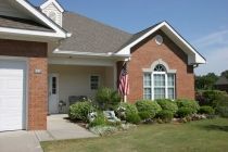 A suburban house with a well-maintained front yard and an American flag displayed on the porch.