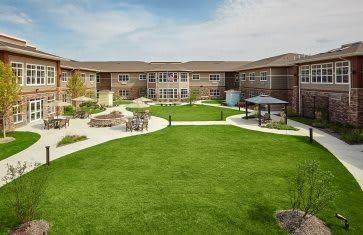 A modern building with a well-maintained lawn and garden area, featuring pathways and seating.