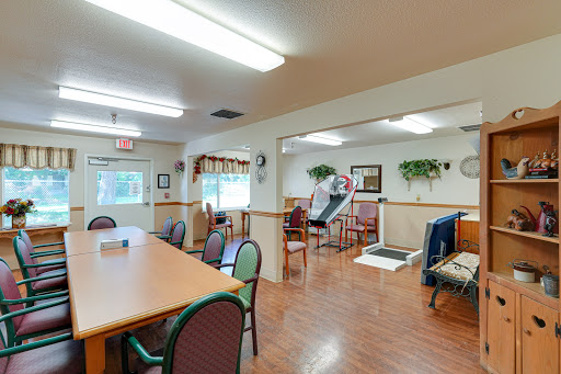 A spacious interior room featuring a dining area with tables and chairs, along with rehabilitation equipment, providing a welcoming environment.