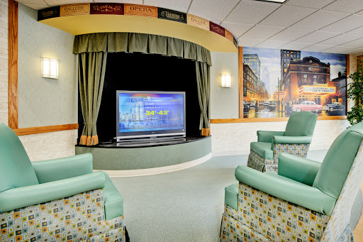 A cozy lounge area in a hospital featuring comfortable seating and a large television for entertainment.