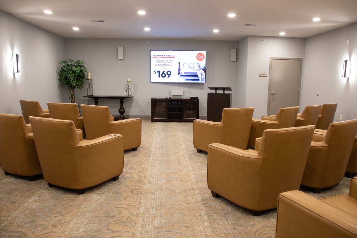 A modern waiting room with comfortable seating and a television screen.
