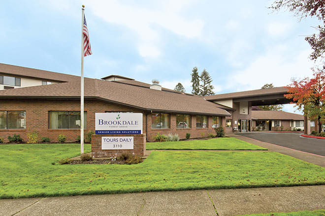A healthcare facility with a sign and an American flag on the lawn.