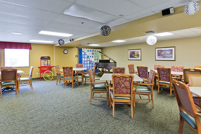 A cozy dining room with tables and chairs, featuring a popcorn machine and decorative elements.
