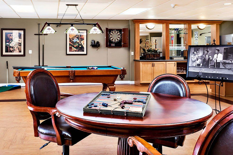 A well-furnished game room featuring a pool table, dartboard, and backgammon set.