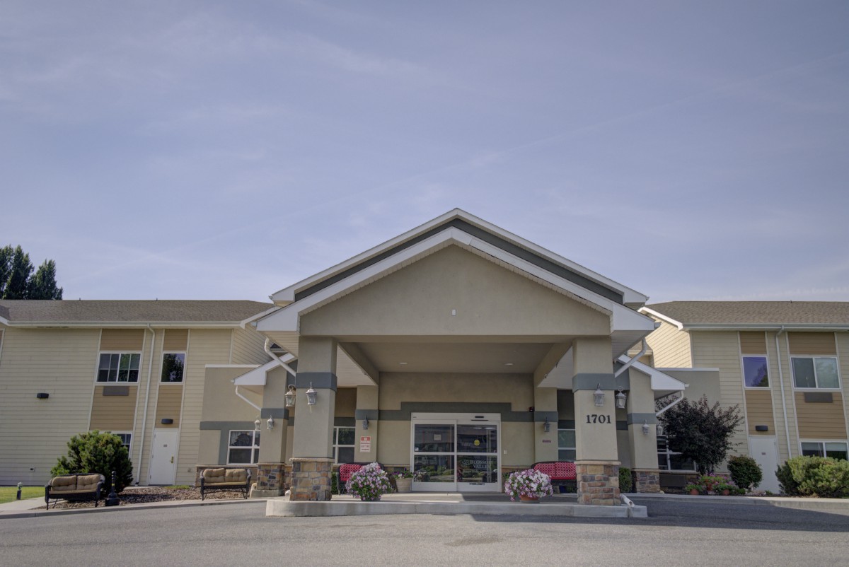 A modern building entrance with large windows and a sloped roof under a clear sky.