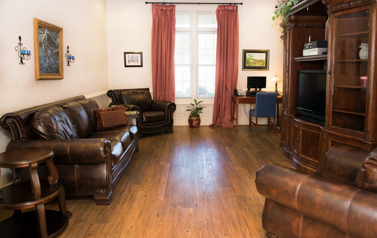 A cozy living room with leather sofas, a television, and a small desk with a computer.