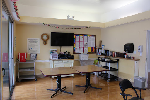 A well-lit meeting room with a large table, television, and storage units.