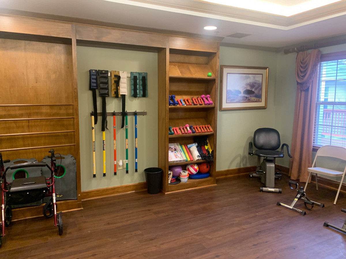 A well-organized exercise room with various fitness equipment and wooden flooring.
