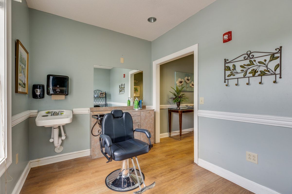 A clean and modern salon with a barber chair, sink, and welcoming decor.