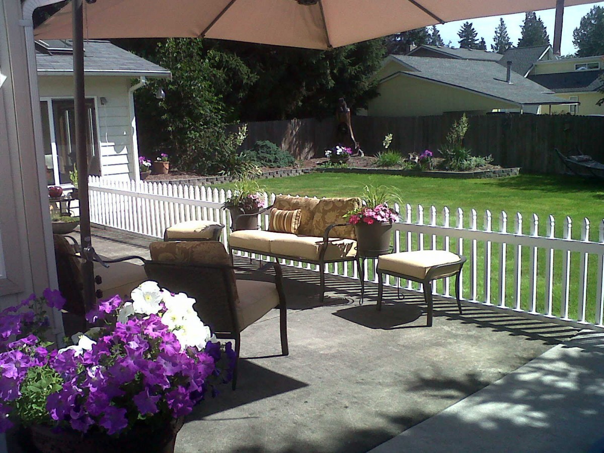 A sunny backyard patio with comfortable seating and colorful flowers.