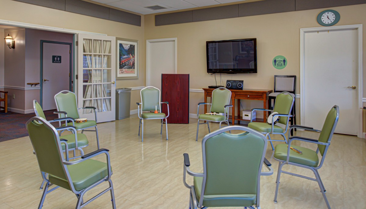 A well-organized meeting room with a circle of chairs, a podium, and a television on the wall.
