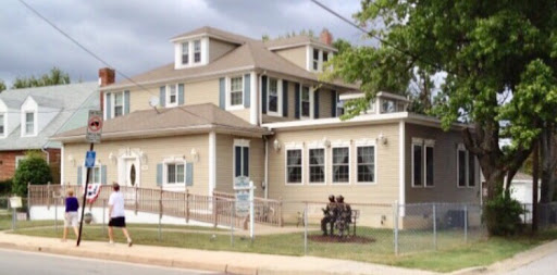 A cozy residential house with a welcoming porch and people enjoying the outdoors.