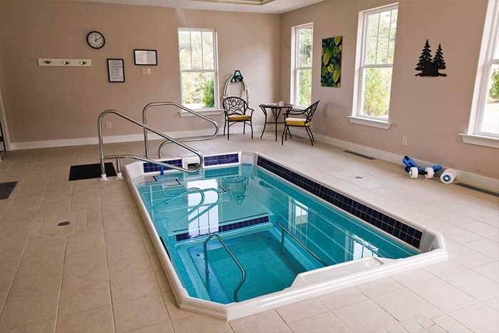 A cozy indoor exercise pool with seating area and natural light.