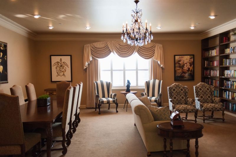 A traditional living and dining area featuring a chandelier, elegant furniture, and framed artwork.