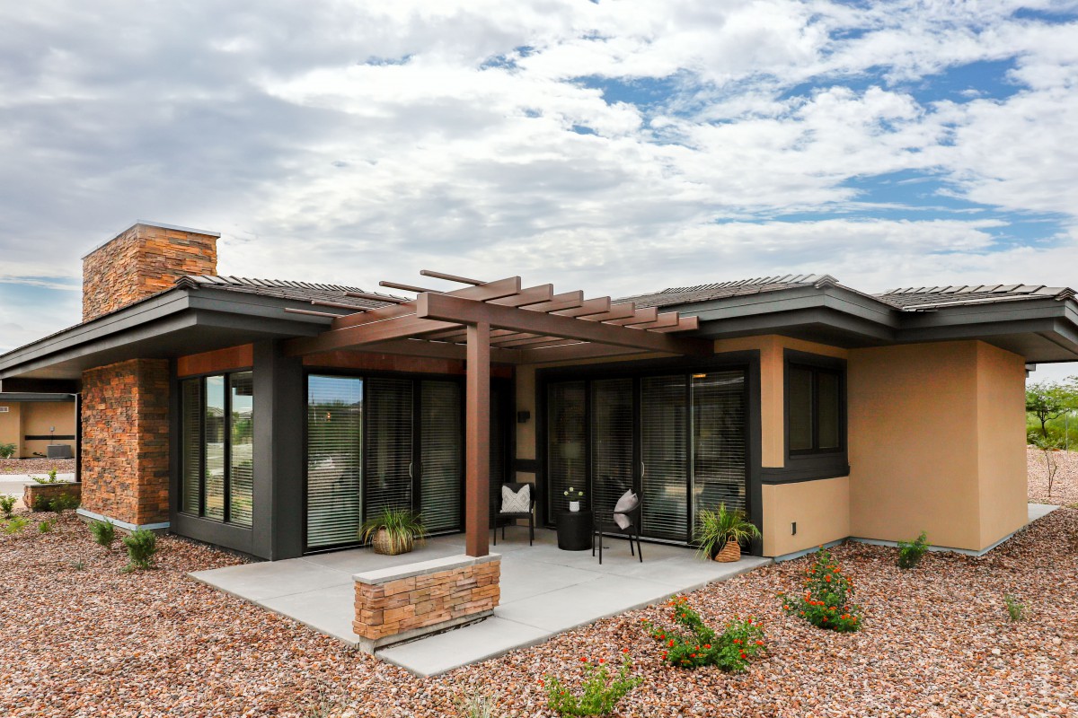 A modern house with a patio and outdoor seating under a cloudy sky.