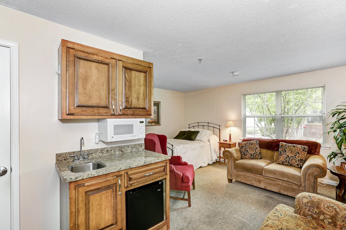 A cozy studio apartment with a kitchenette, bed, and small living area.