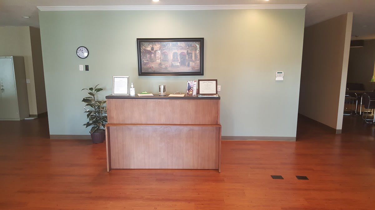 A well-organized reception area with a wooden desk, wall art, and a potted plant.