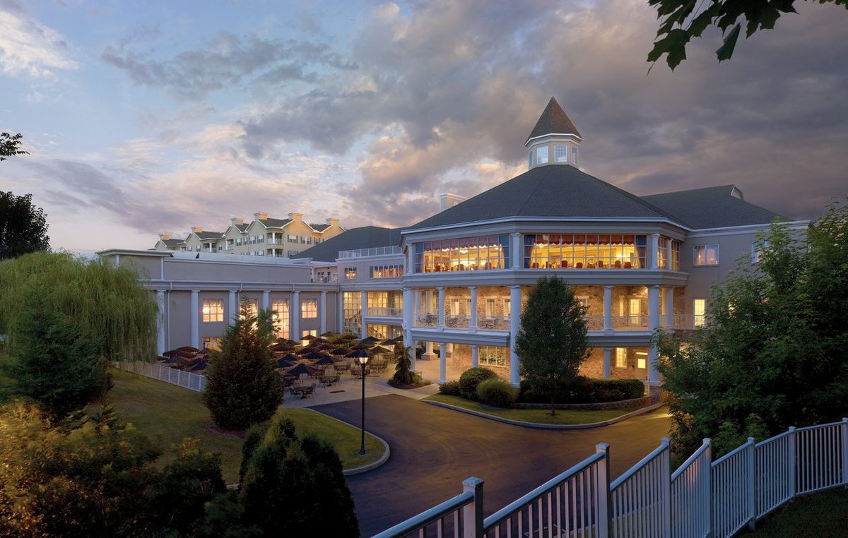 A grand hotel building illuminated in the evening with well-maintained landscaping.
