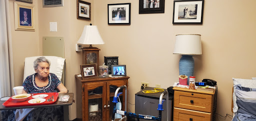 A cozy corner of a room featuring a wooden side table, decorative lamp, and framed photos.
