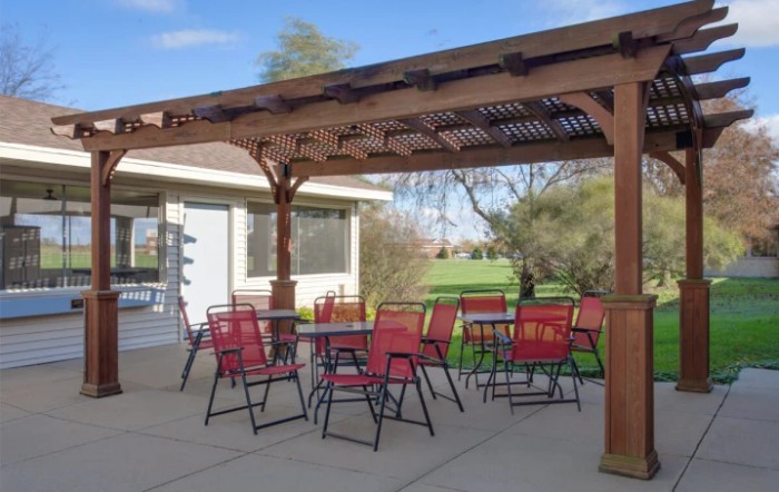 A cozy outdoor patio with red chairs and a pergola, perfect for relaxing in the garden.