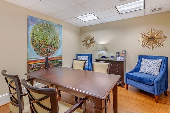A well-decorated office meeting room featuring a large table, chairs, and colorful artwork on the wall.