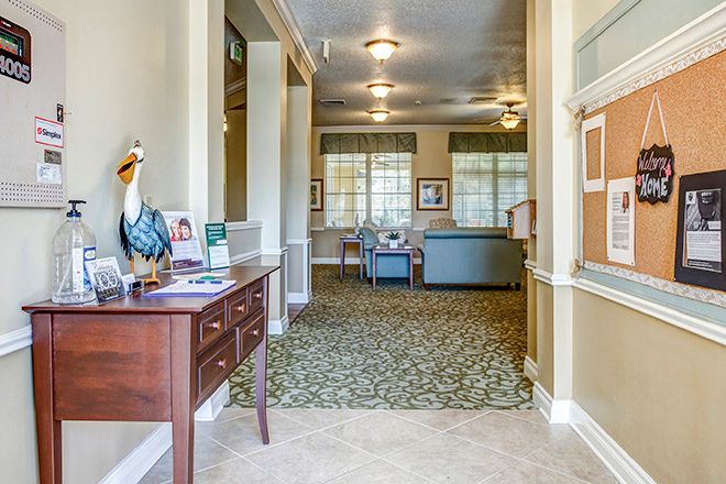 A well-lit hallway with decorative furnishings and carpeted flooring leading to a seating area.