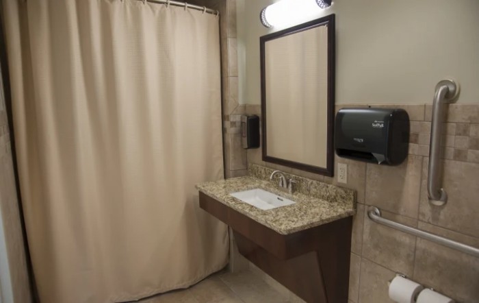 A clean bathroom featuring a granite countertop sink and a shower area with a curtain.