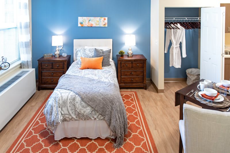 A modern bedroom with a single bed, blue walls, and orange accents.