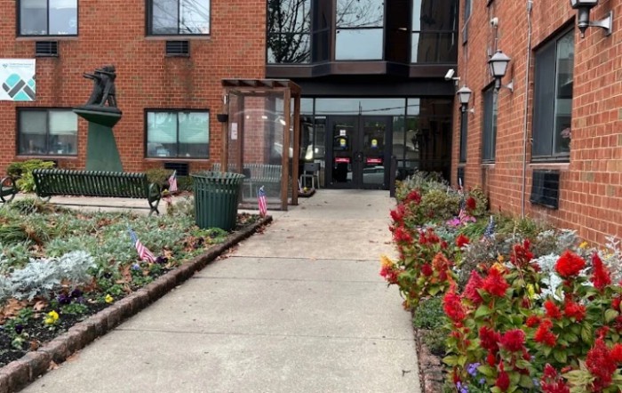 Entrance to a red brick building with colorful flowers lining the pathway.