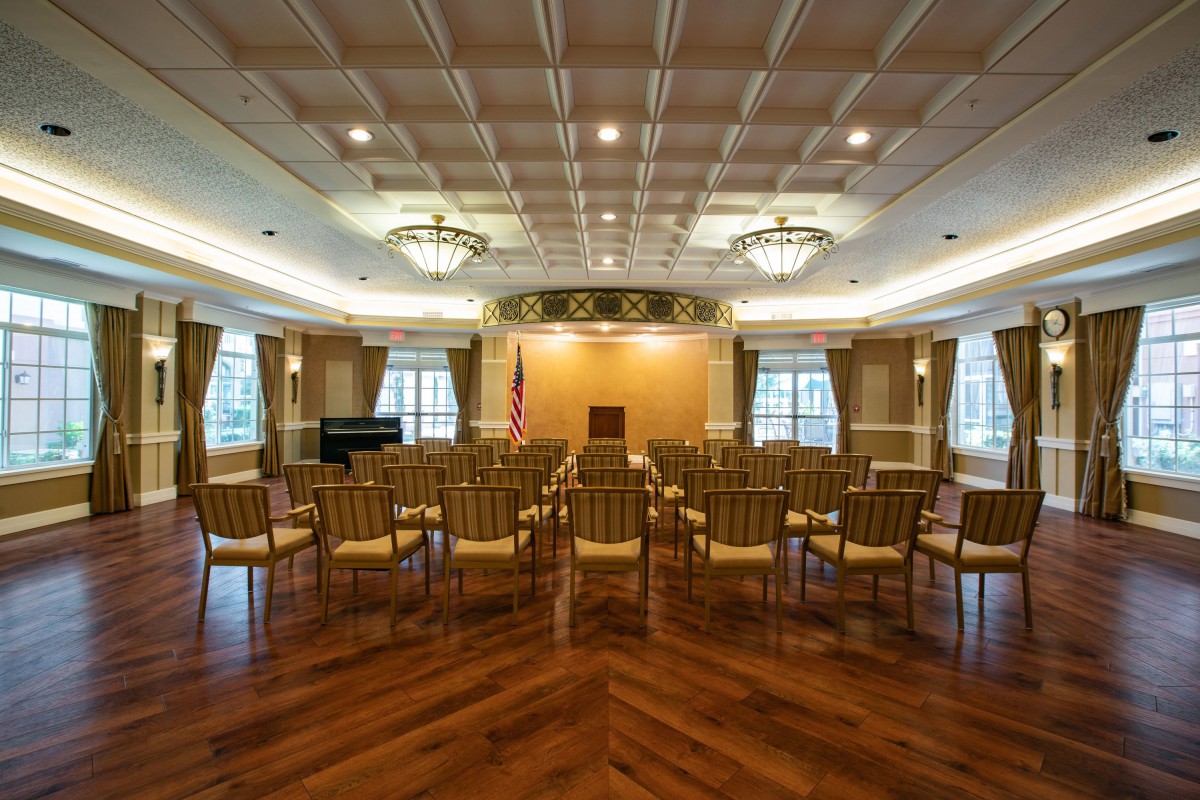 An elegant conference room set up for an event, featuring rows of chairs facing a podium and the national flag.