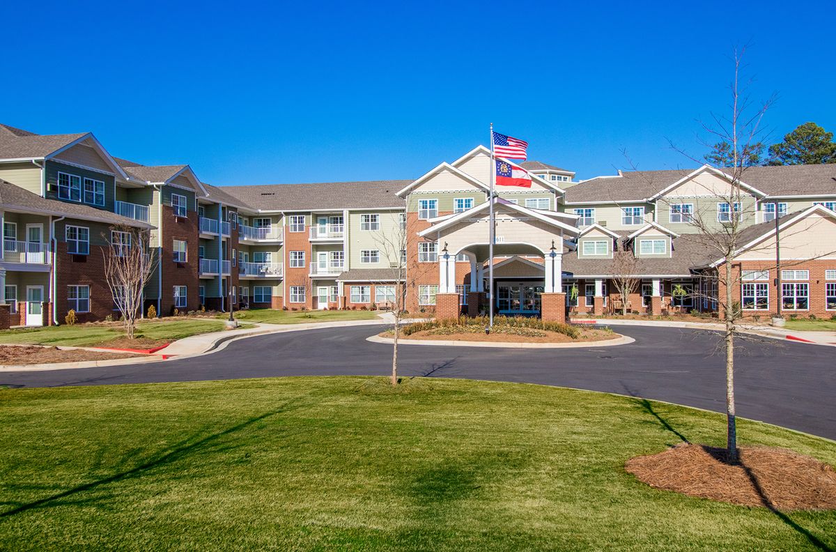 A modern residential apartment building with an entrance and flags flying outside.