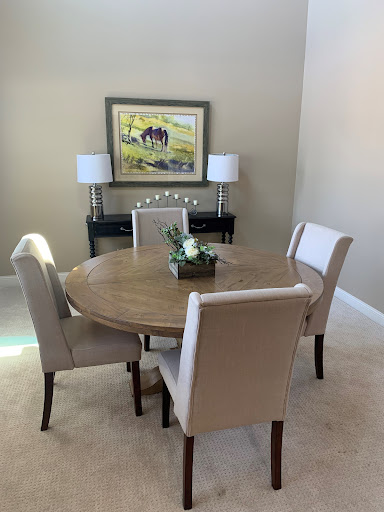 A cozy dining area featuring a round table surrounded by upholstered chairs, complemented by elegant lamps and wall art.