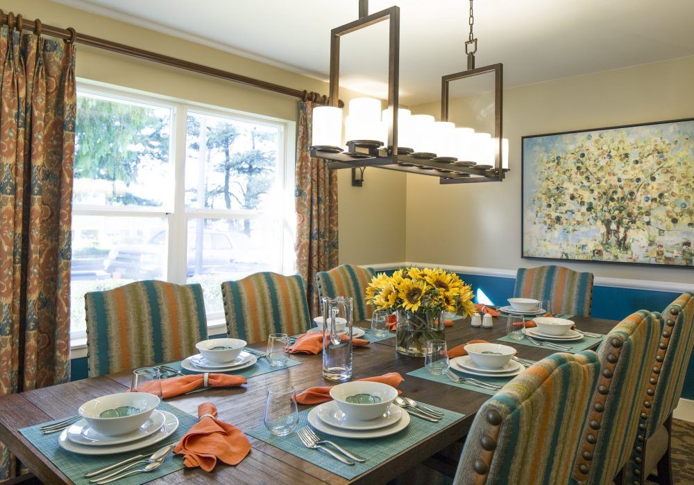 A well-decorated dining room with a table set for a meal, featuring striped chairs and a floral centerpiece.