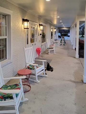 A long porch with white rocking chairs lined up along the walls.